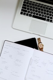 white book near Macbook Pro laptop