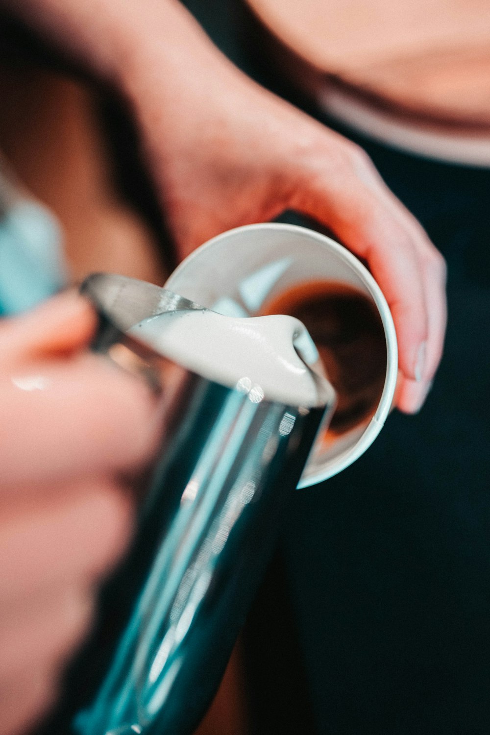 persona sosteniendo una taza de acero inoxidable gris mientras sirve café