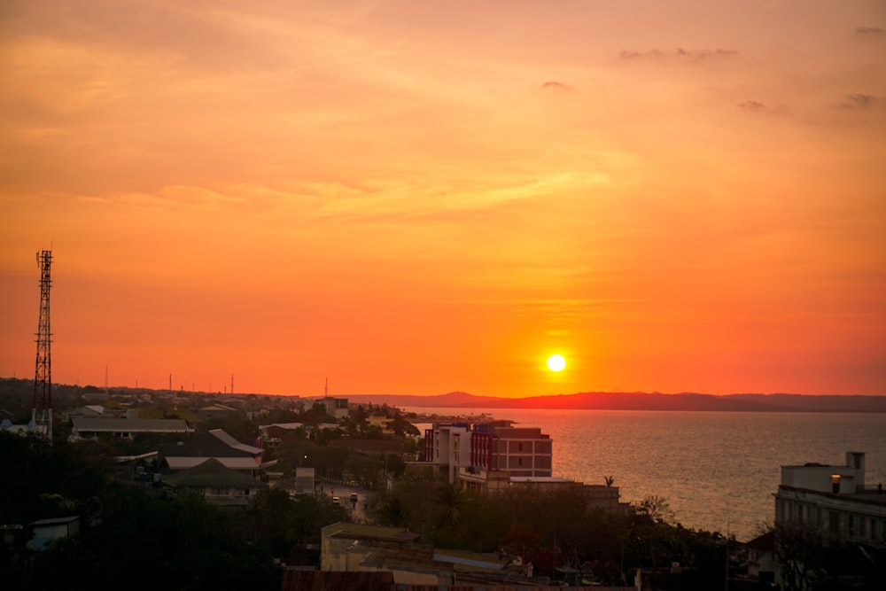 orange setting sun over city by the sea