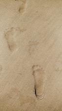 A close-up of footprints on a sandy path symbolizing gradual progress.