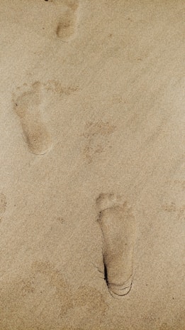 A close-up of footprints on a sandy path symbolizing gradual progress.