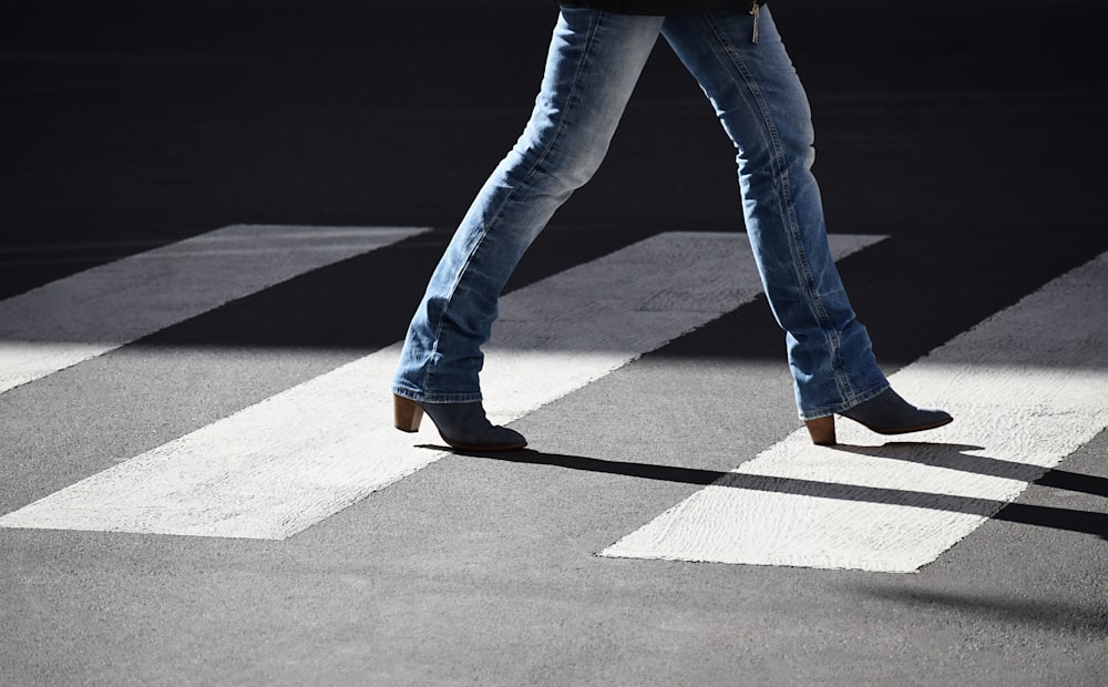 person wearing jeans walking at pedestrian lane