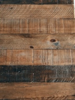 Wooden planks with a rustic appearance, featuring visible grain patterns and variations in color.
