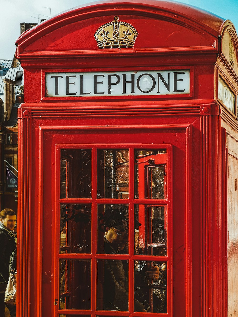 person inside red telephone booth during daytime