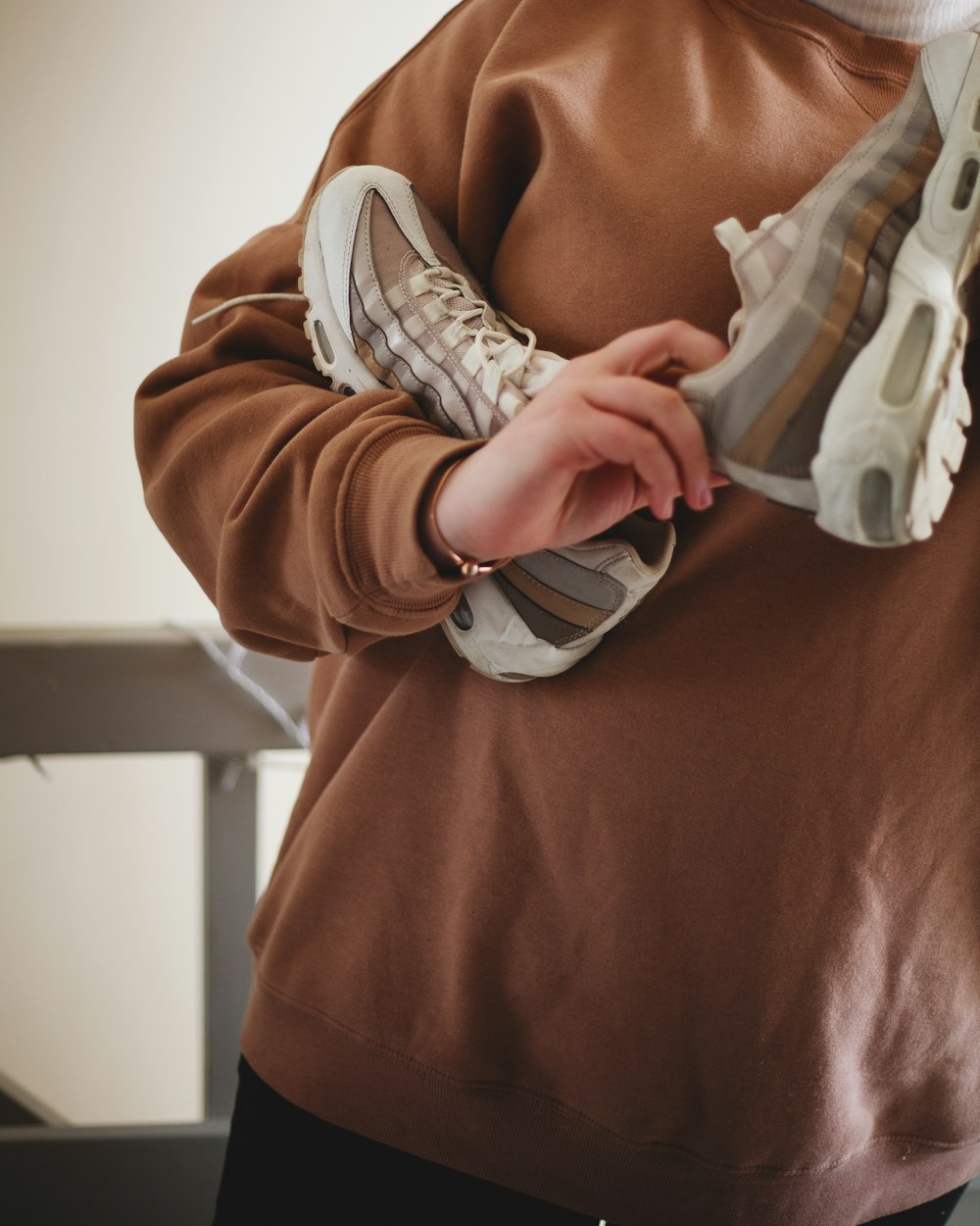 person holding brown-gray-and-white shoes