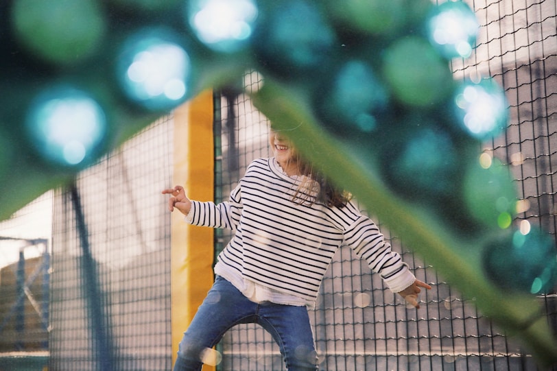 girl wearing white and black striped long-sleeved shirt playing in playground during daytime