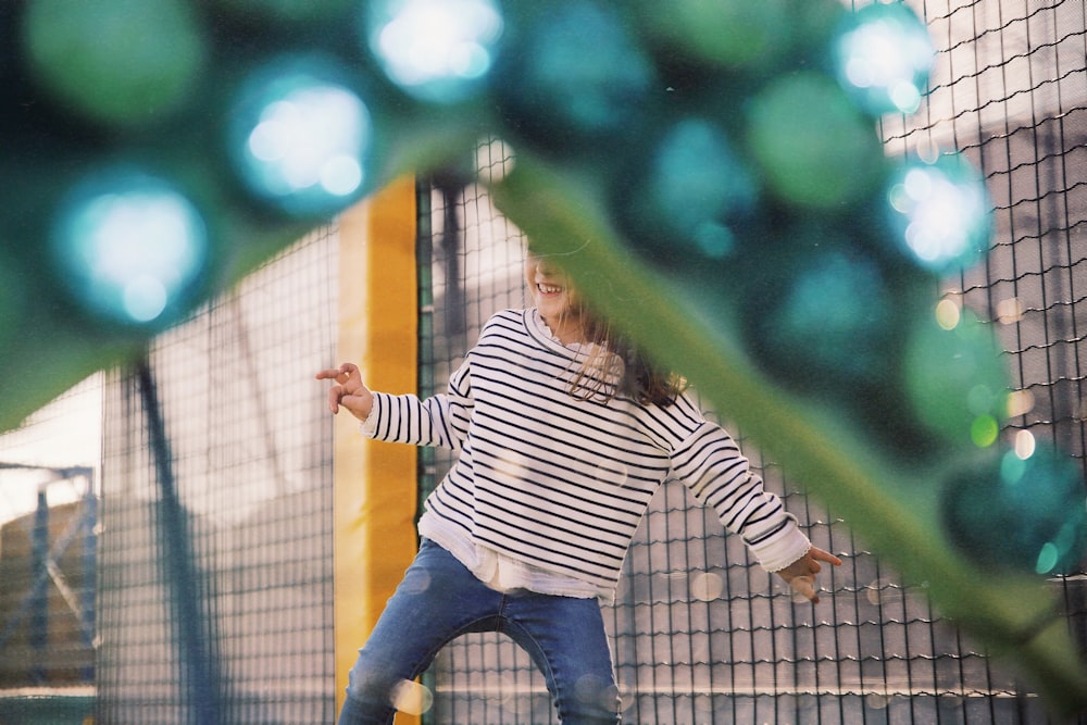 Ragazza che indossa una camicia a maniche lunghe a righe bianche e nere che gioca nel parco giochi durante il giorno