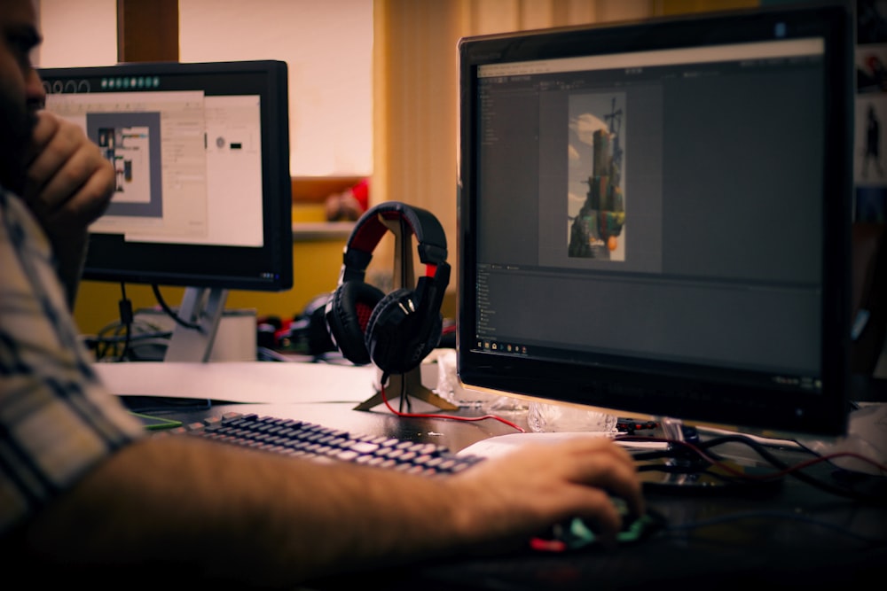 person holding mouse in front of monitor