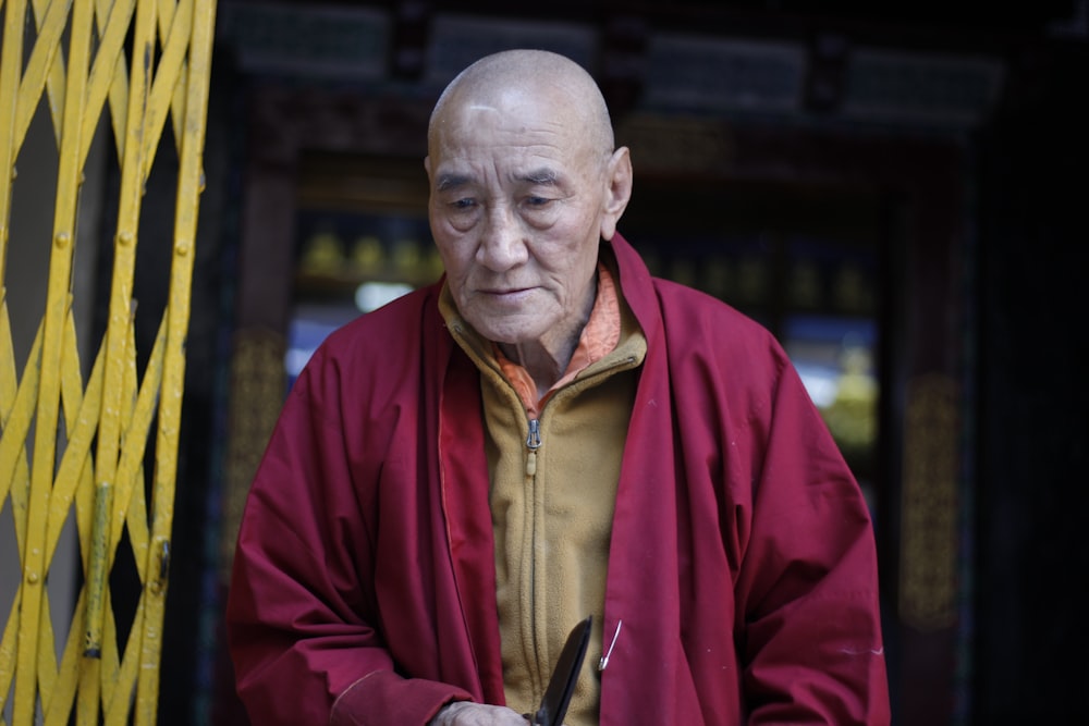 man in red jacket standing beside yellow gate