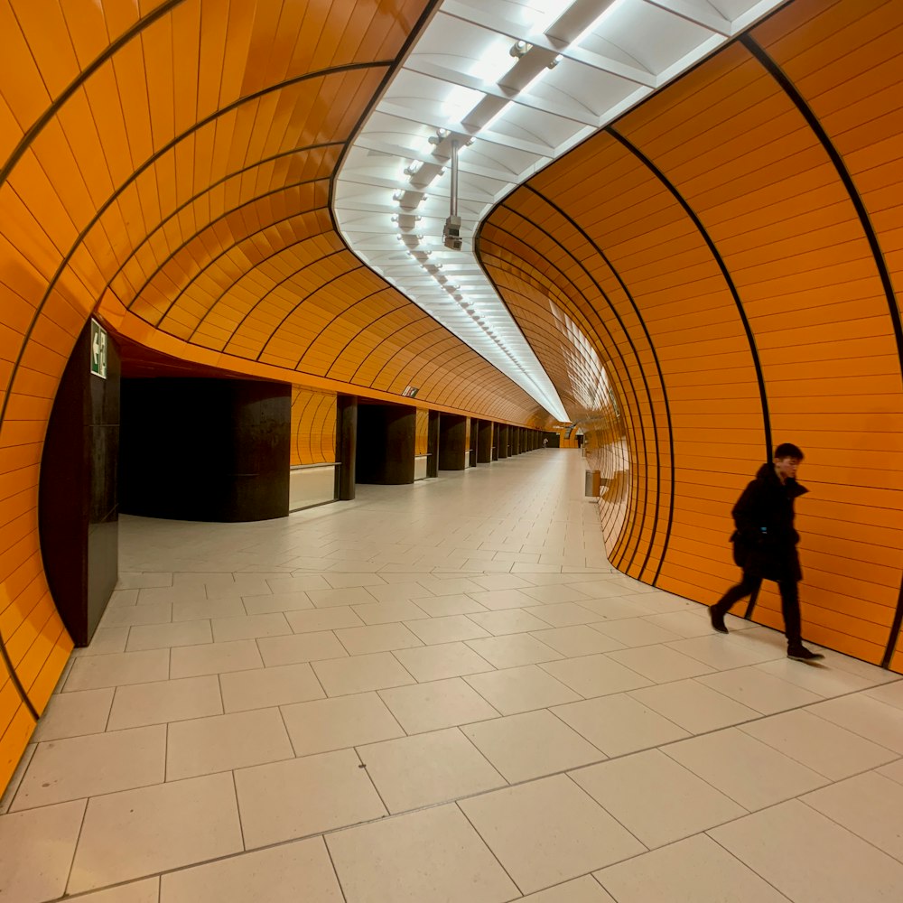 person wearing black coat walking inside brown painted wall