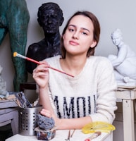 woman leaning on table and holding paint brush