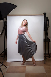Sarah C posing glamorously backstage with sparkling accessories and vibrant pink backdrop