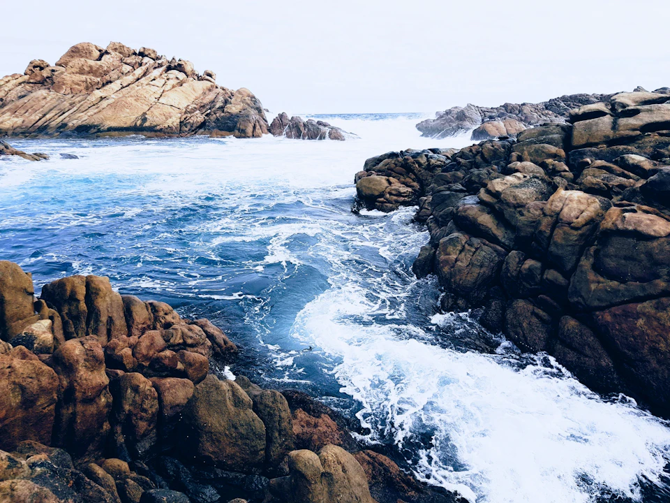 Rocky coastline features large jagged rocks and boulders scattered along the ocean's edge