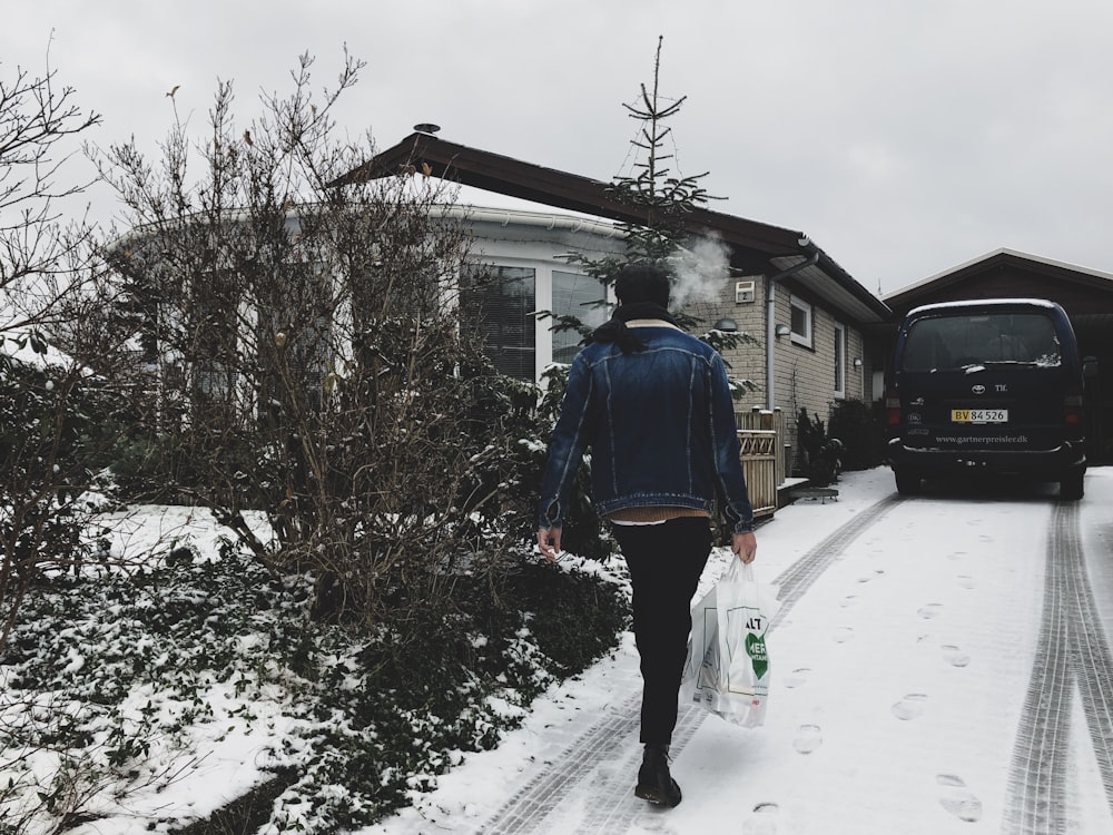 Mulher que carrega saco plástico andando perto de casa durante o inverno