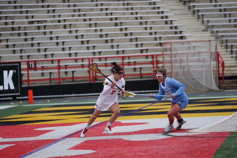 two women playing lacrosse during daytime