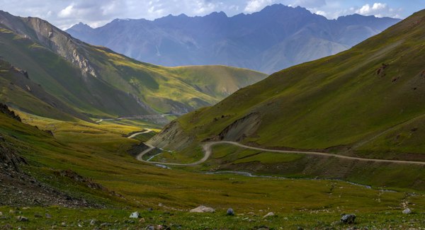 Winding road between green grassy hills — Osh, Kyrgyzstan