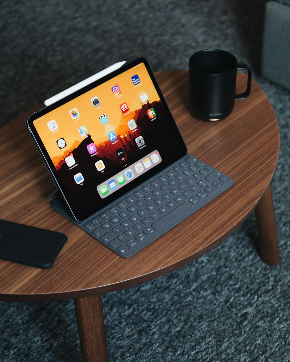 black tablet computer with gray portable keyboard on brown wooden coffee table