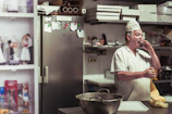 Technician in uniform inspecting a residential kitchen for pests.