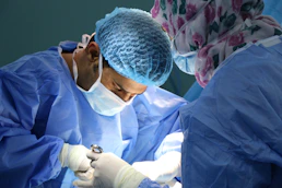 Medical professionals performing a procedure in a hospital operating room.