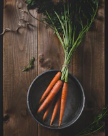 A rustic wooden table scattered with vibrant beets and carrots, their leafy tops still attached.