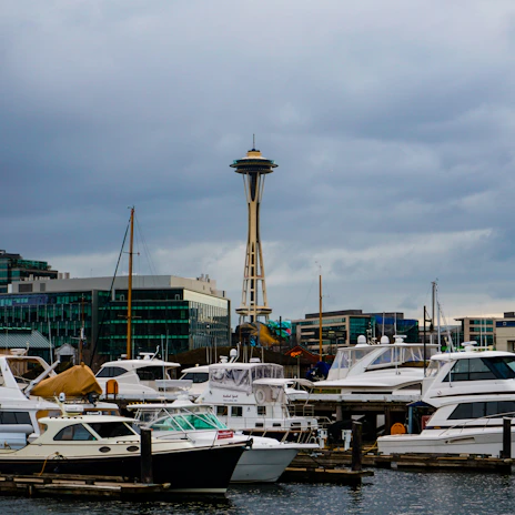 A HarborLift tow truck assisting a stranded vehicle on a rainy Seattle street at dusk.
