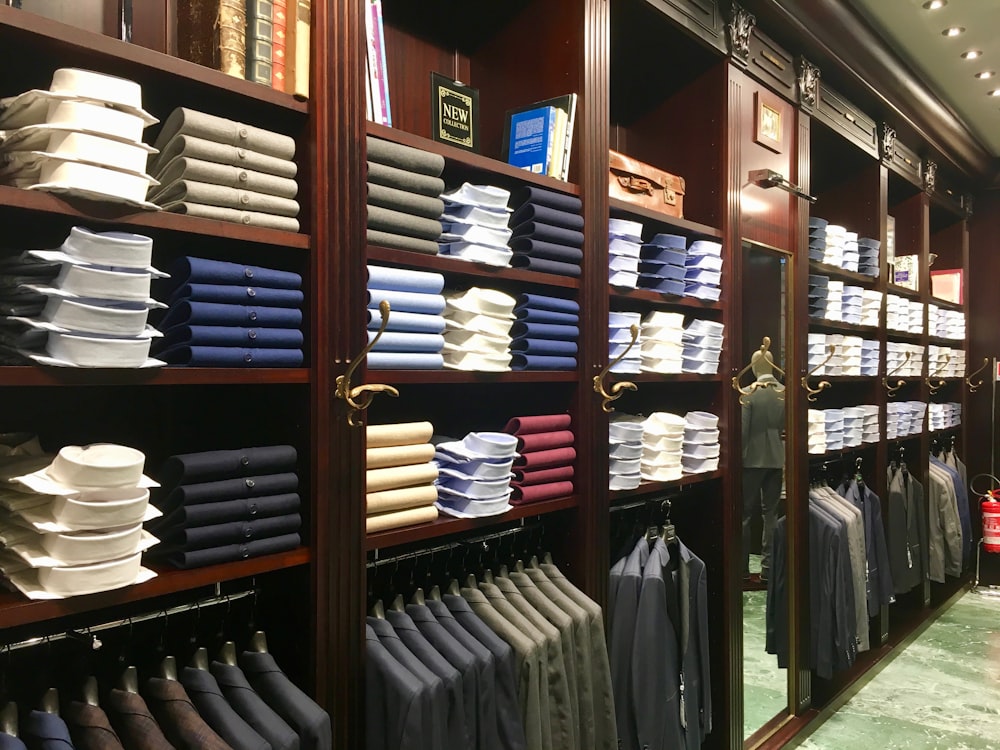 assorted-colored clothes on brown wooden shelf