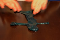 Hands stretching a glossy, translucent slime with glitter suspended inside.