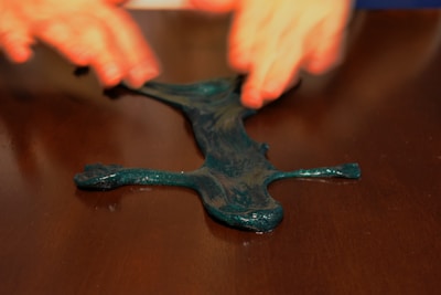 Close-up of vibrant, colorful slime textures stretched and twisted on a wooden table.