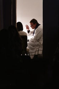 man wearing white bathrobe sitting on bed