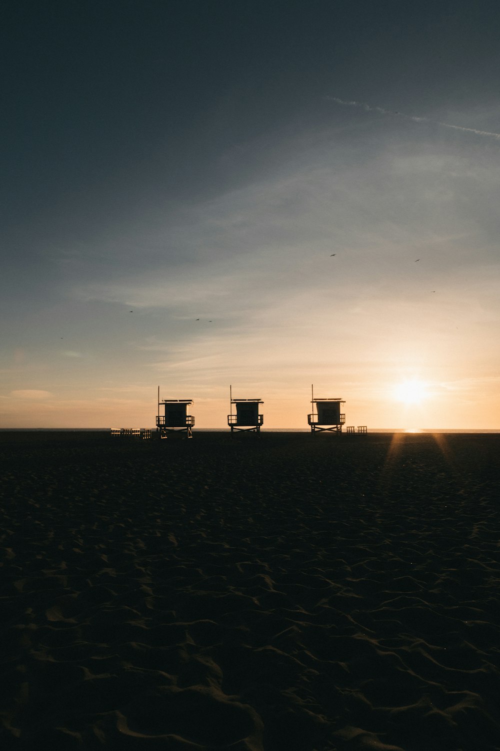 silhouette of three beach watch houses