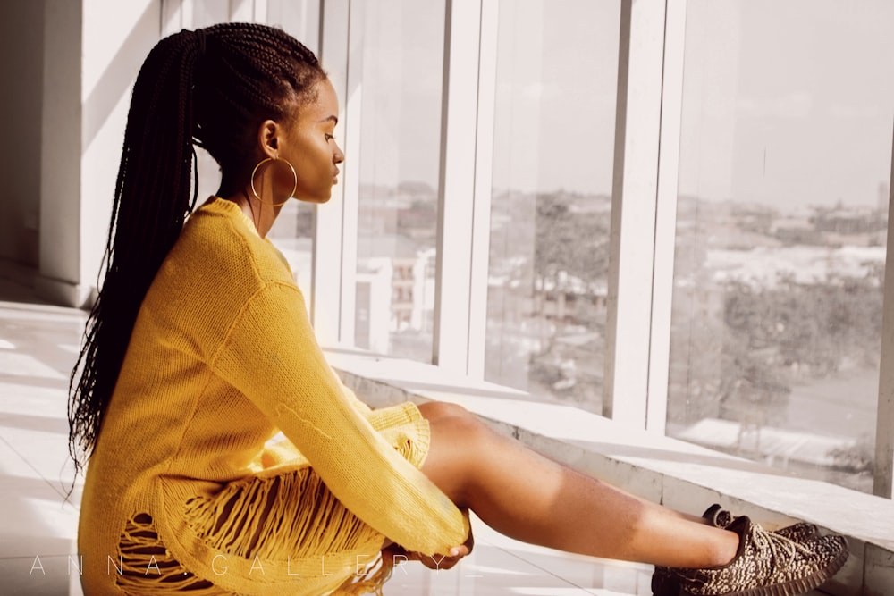 woman wearing long-sleeved dress sitting near window