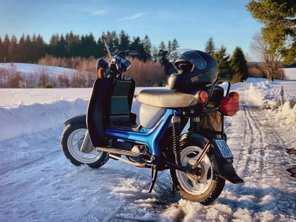 blue motor scooter parked in the road during daytime