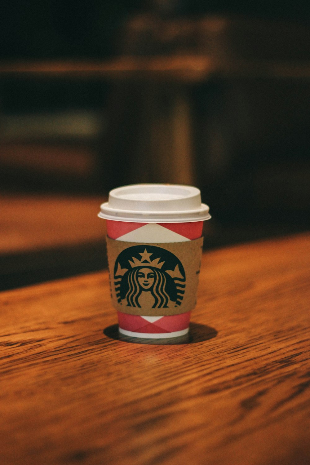 white and pink Starbucks tumbler on brown surface