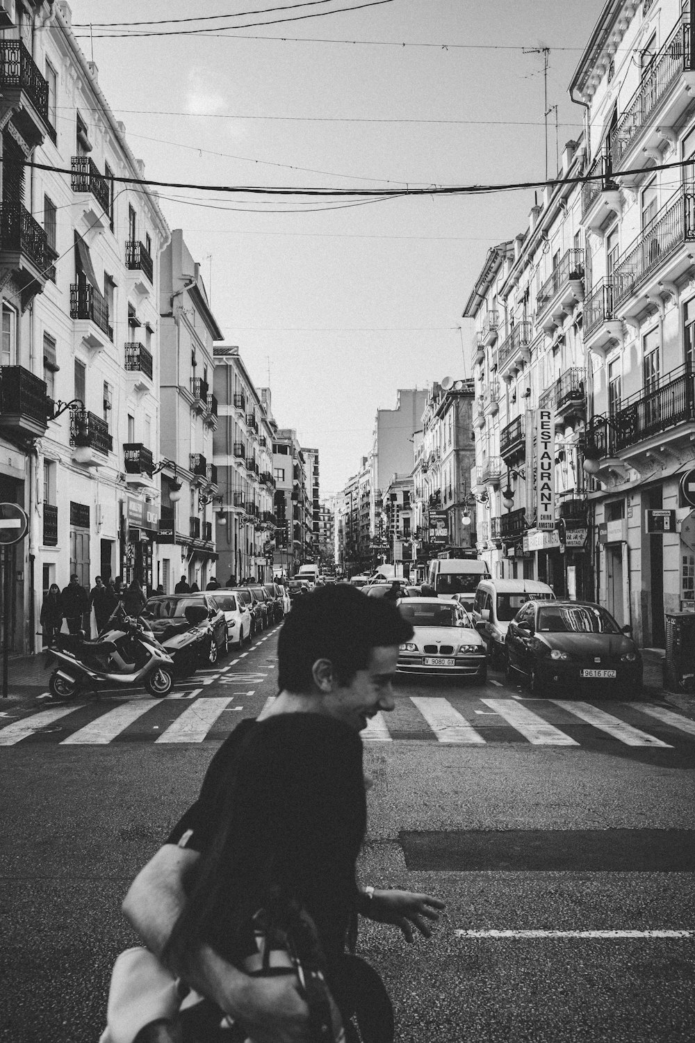 grayscale photo of man and woman crossing street