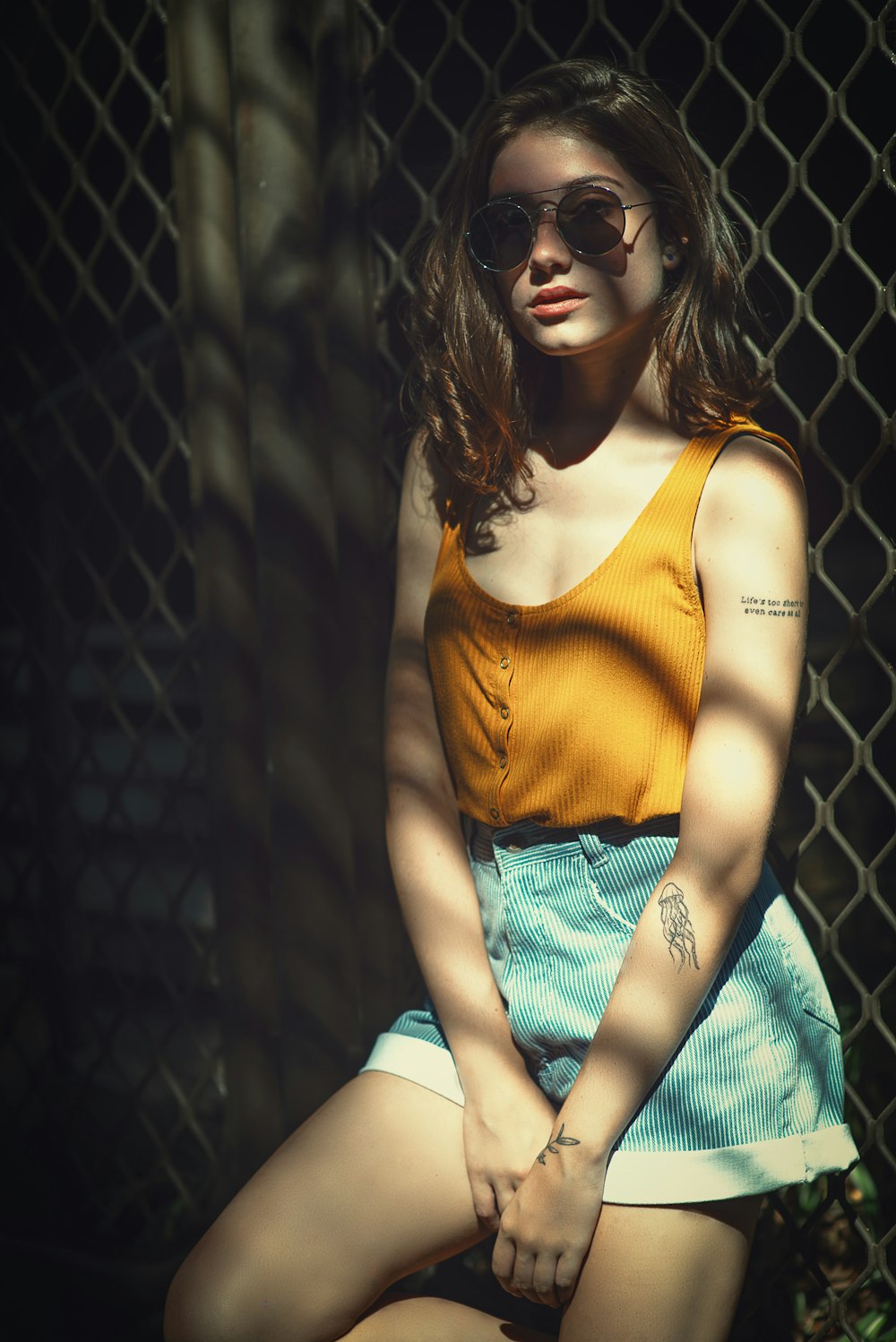 woman wearing yellow tank top lying on cyclone fence