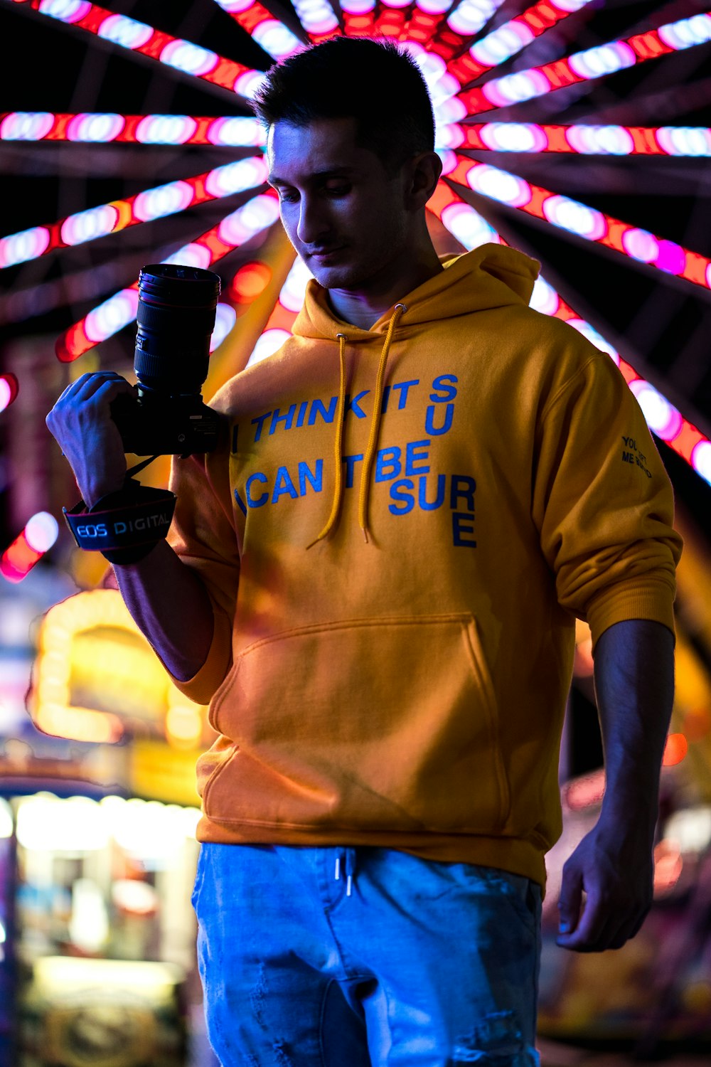 hombre con jersey amarillo sosteniendo una cámara DSLR negra