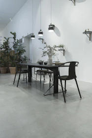 A sleek dining area featuring minimalist chairs and a stylish table under pendant lights.