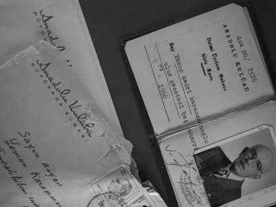 Several documents and an envelope are displayed, including a membership card with printed text and a black-and-white photograph of an older man wearing glasses. The envelope has handwritten addresses and a few stamps attached.