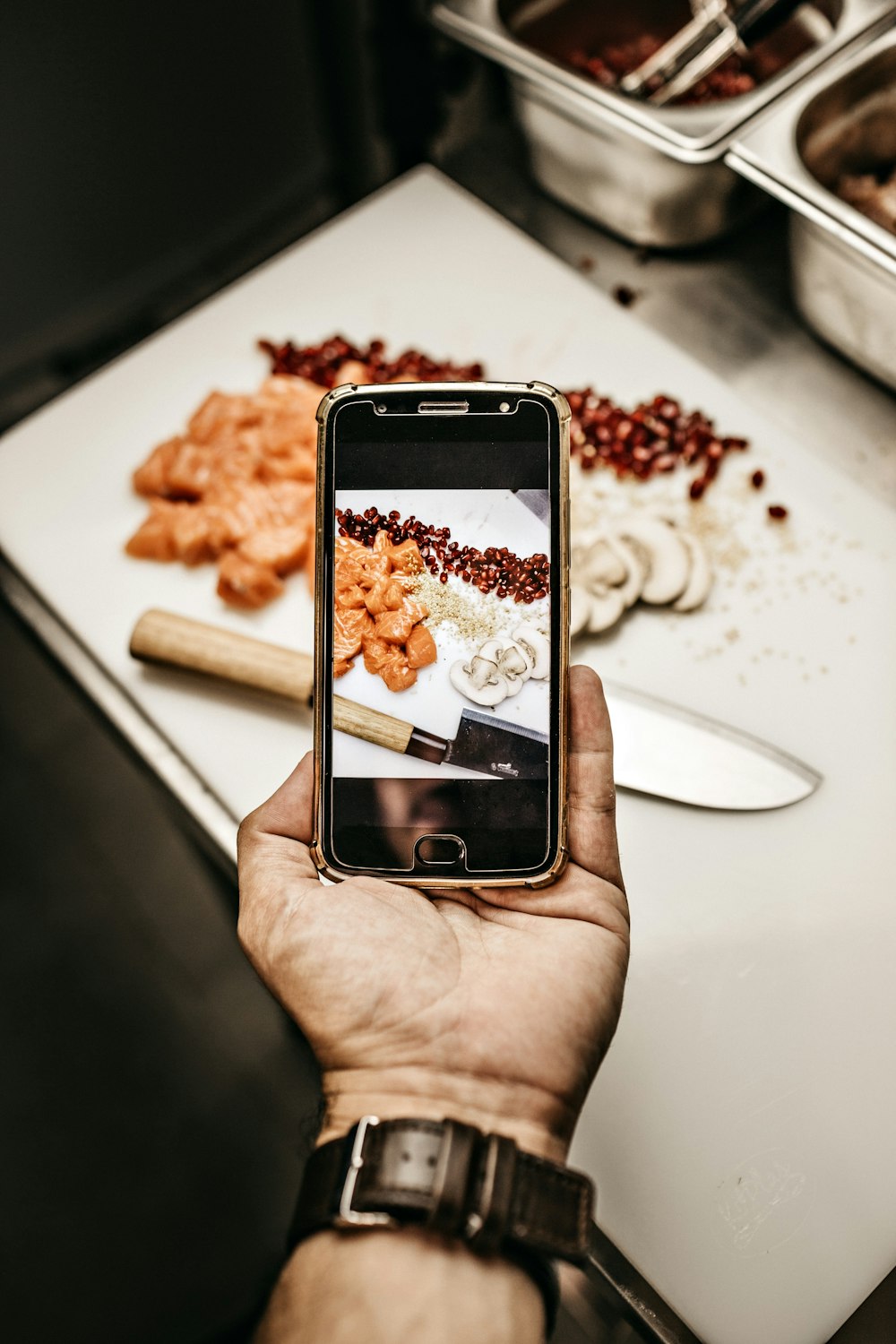 person holding smartphone while taking photo of cooked food