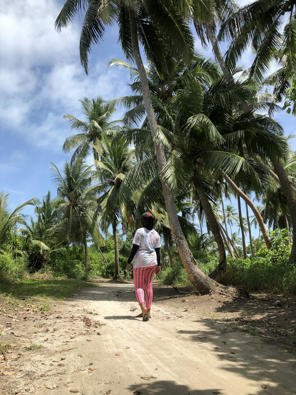 femme portant un pantalon rose à côté d’un cocotier