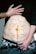 A person's torso with a prominent vertical scar down the middle of the abdomen. There are various words written around the scar, such as confusion, hope, inclusion, function, presence, fight, repair, pain, healing, redemption, fear, and loss. The person is holding up their shirt to reveal the scar and the words, and they are wearing jeans and patterned underwear.