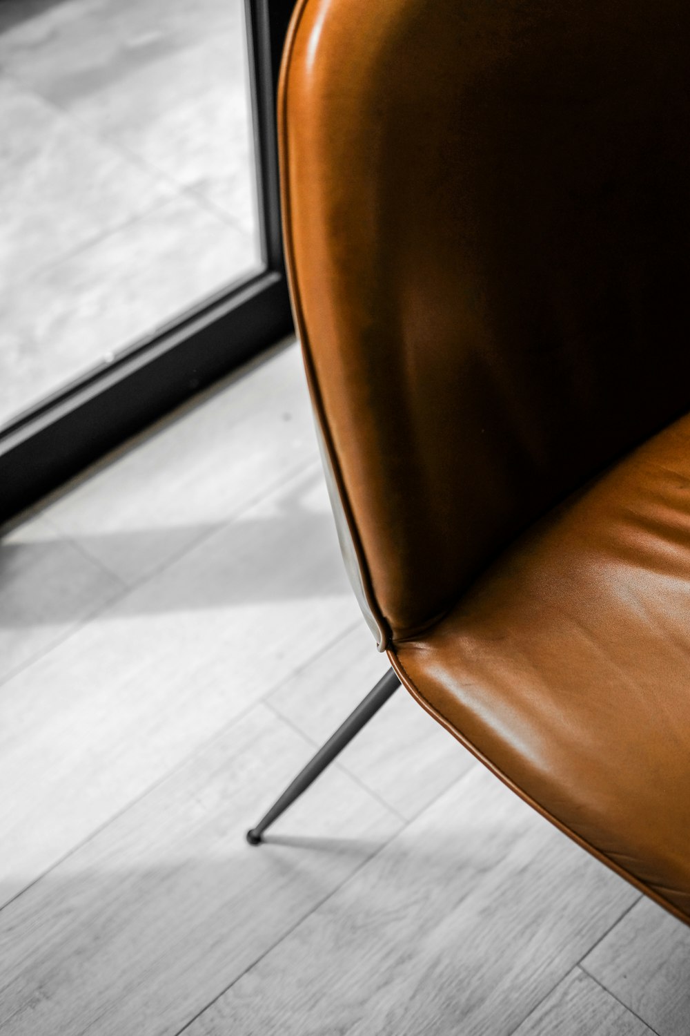 a brown leather chair sitting in front of a window