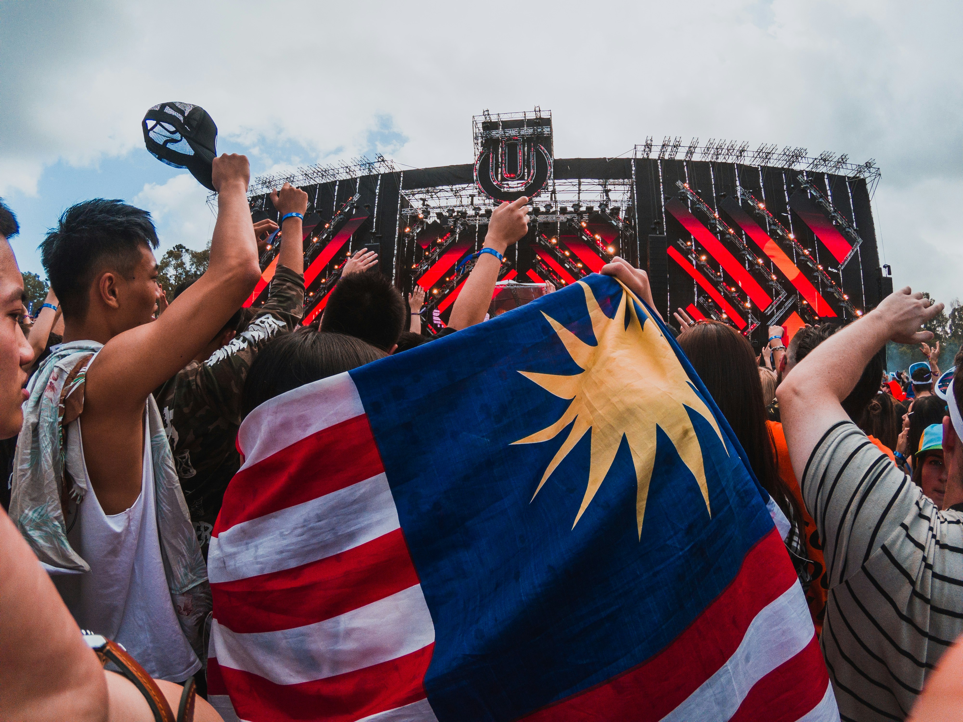 person holding US flag at crowd under cloudy sky during daytime