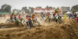 Riders launching off a dirt ramp during a sunny motocross race at sõmerpalu track