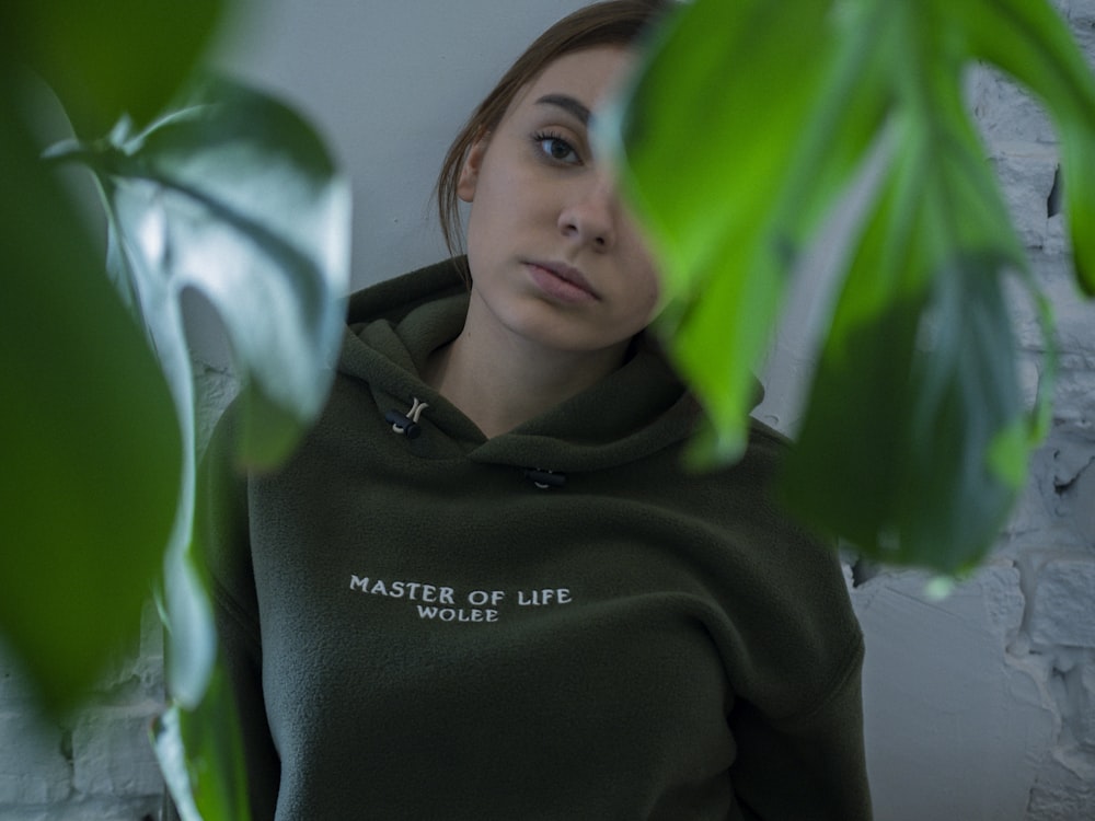 woman in black hoodie behind plant