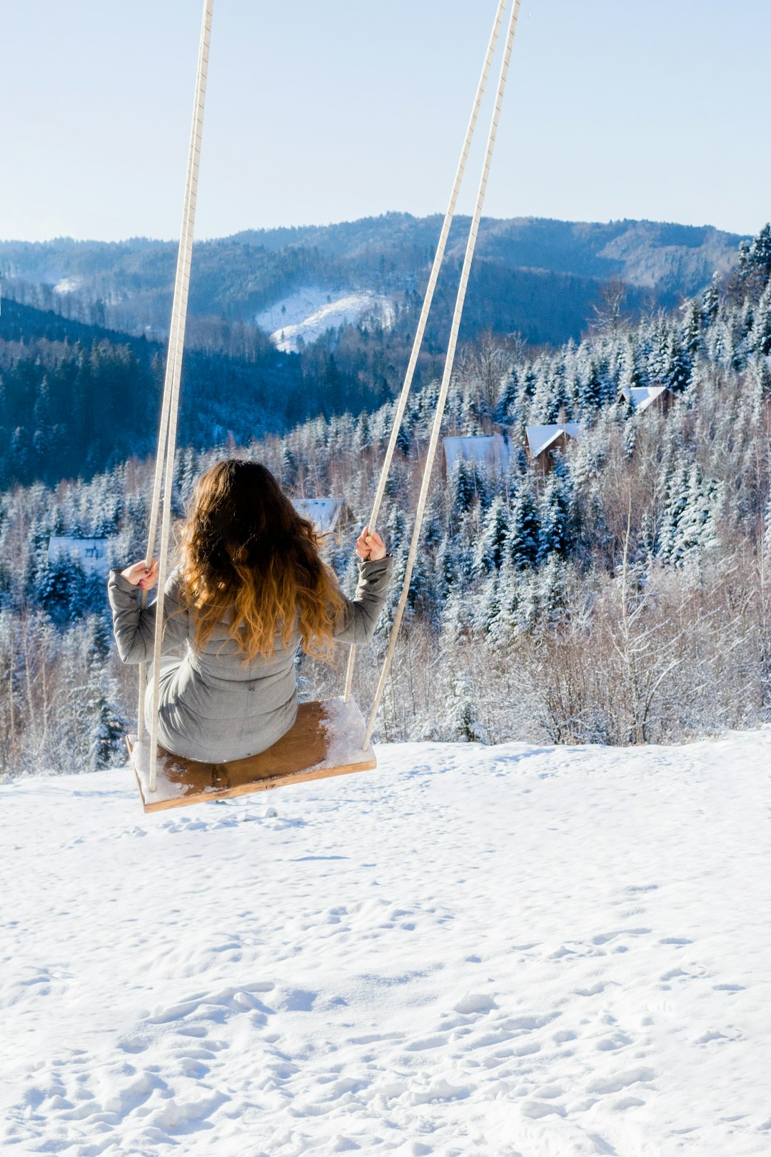 woman sitting on swing at the field covered in snow during day