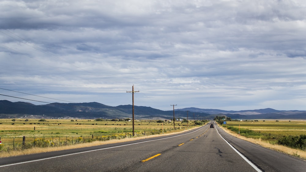 white cloudy sky over long straight highway