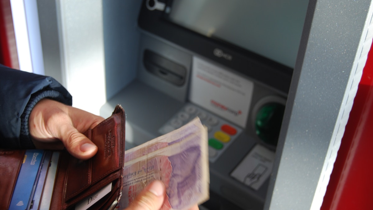 person holding brown leather wallet and banknotes