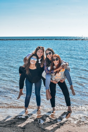 Group of friends laughing on a sunny beach with clear blue water