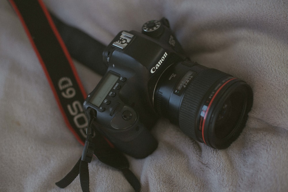 black Canon camera on grey bed linen